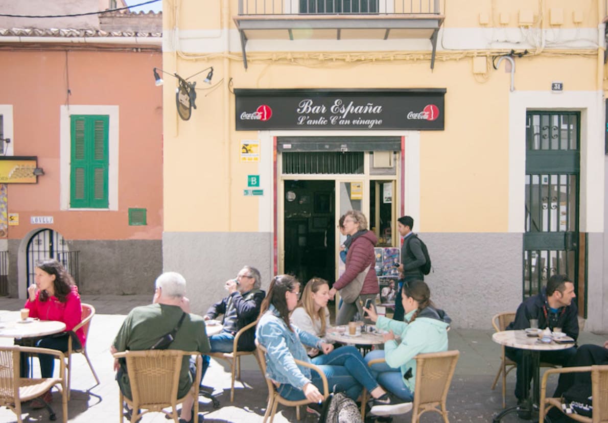 Fachada y terraza llena de clientes del establecimiento emblemático Bar España
