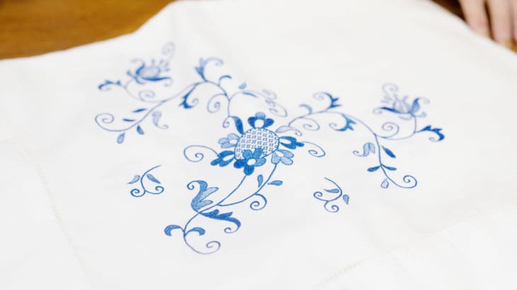 Muestra de bordado floral de color azul en tela blanca, establecimiento emblemático Bordados Valldemossa